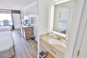 Hotel room with two beds, a TV, desk, and access to the hotel pool and bathroom vanity.