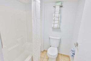 Penthouse-style white bathroom with shower, stacked towels, and toilet paper near Fort Walton Beach.