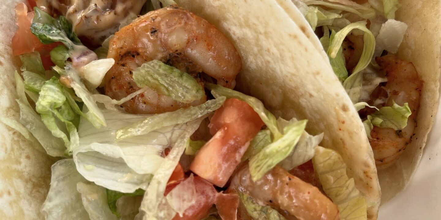 Close-up of shrimp tacos with lettuce and diced tomatoes at a Fort Walton Beach hotel.