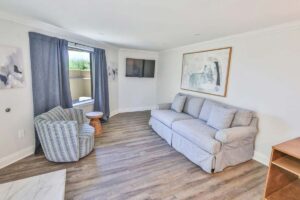 Bright Fort Walton Beach penthouse living room with gray sofa, TV, wall art, and window views.