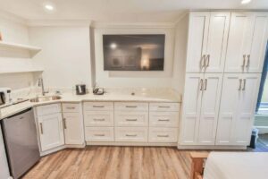 Modern kitchenette with white cabinets, wood flooring, and views of the beach from a penthouse.