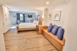 Spacious, modern penthouse bedroom with wooden floors, large bed, and cozy seating area.