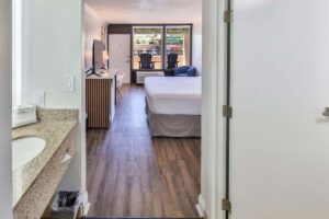 Hotel room with bed, TV, chairs, and balcony view at a Fort Walton Beach beachfront resort.
