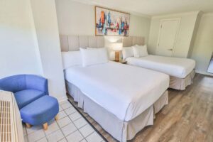 Hotel room with two double beds, abstract wall art, and wood-look flooring near Fort Walton Beach.