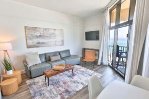 Bright living room with modern furniture, wall art, and ocean-view balcony in Fort Walton Beach.